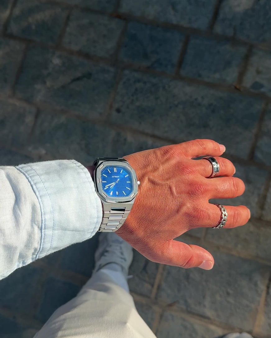 D-FFRENT The Aura Blue stainless steel men's watch worn outdoors in natural sunlight.